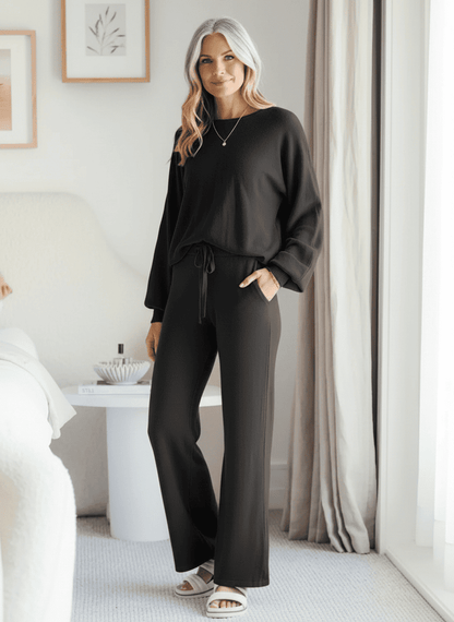Woman wearing black Comfee wide leg lounge set styled in bright neutral bedroom